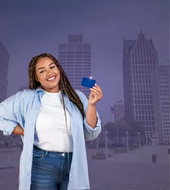 woman holding up a visa card with Detroit city in the background